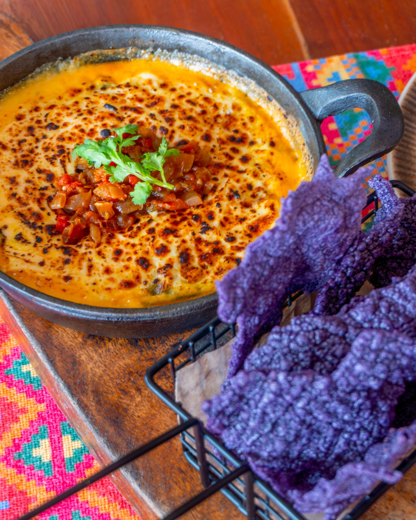 Caldereta enchiladas bubbling in a cast-iron pan, served with Salsa's signature purple nacho chips.