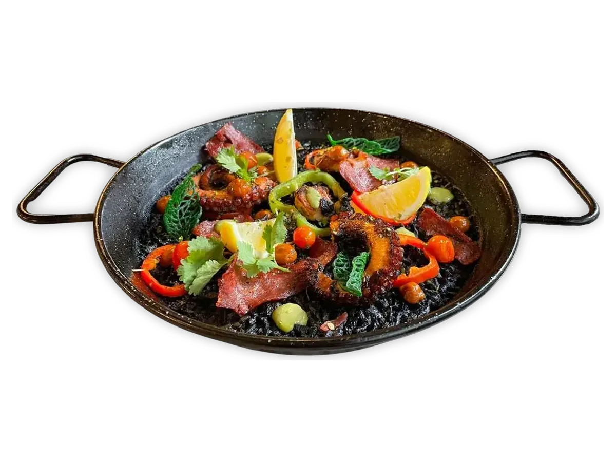 Black squid-ink rice with octopus, peppers and lemon in a paella pan.
