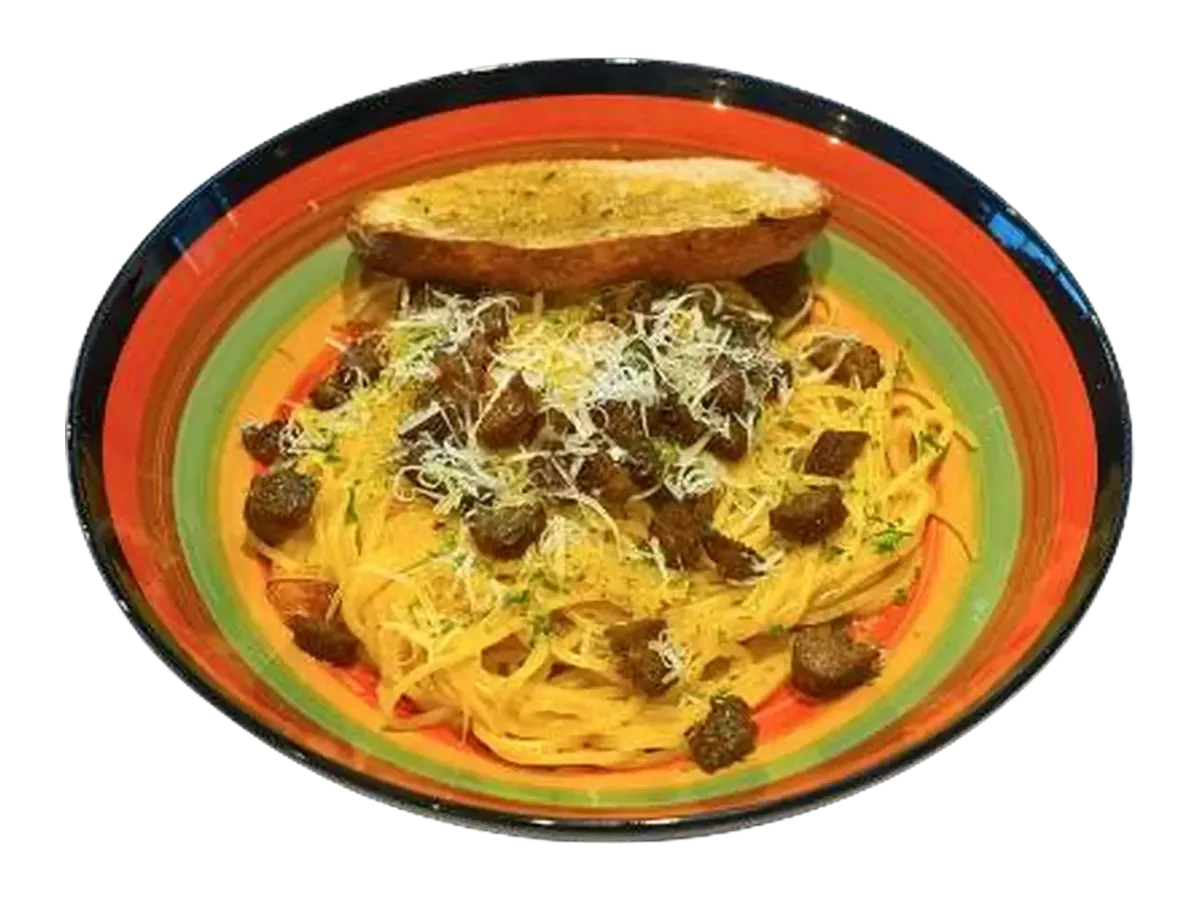 Spaghetti carbonara topped with chorizo, parmesan and garlic toast in a striped bowl.