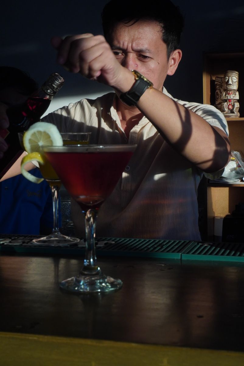 A Salsa bartender carefully finishing a deep-red cocktail at the bar.