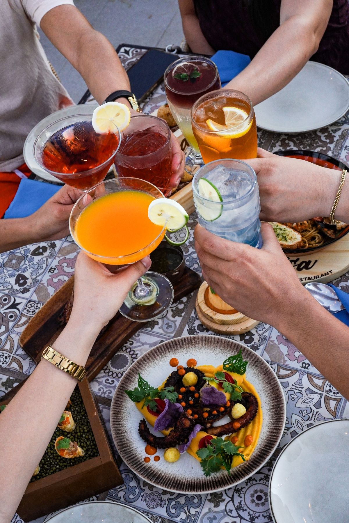 Friends clinking signature cocktails over a table of shared plates at Salsa.