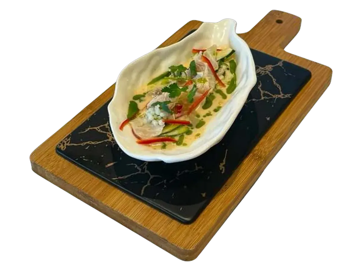 Snapper ceviche in coconut milk, served in a shell-shaped bowl on a marble board.