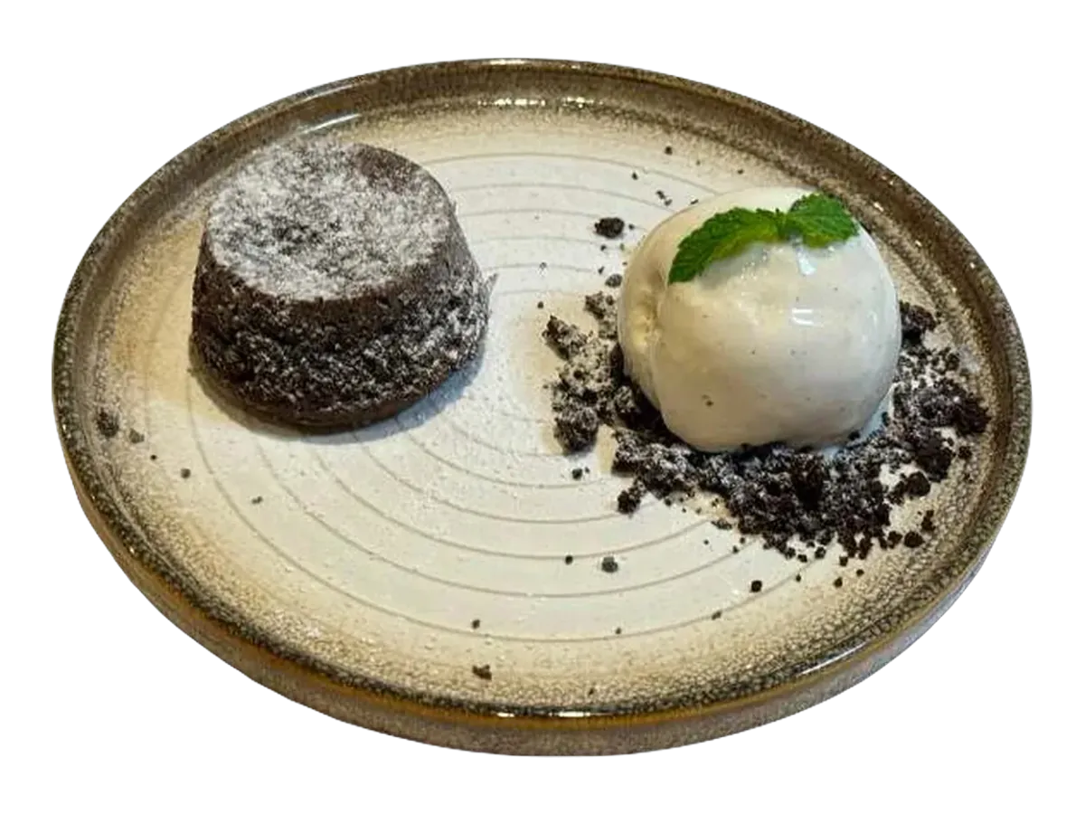 Chocolate lava cake dusted with sugar beside a scoop of vanilla ice cream.